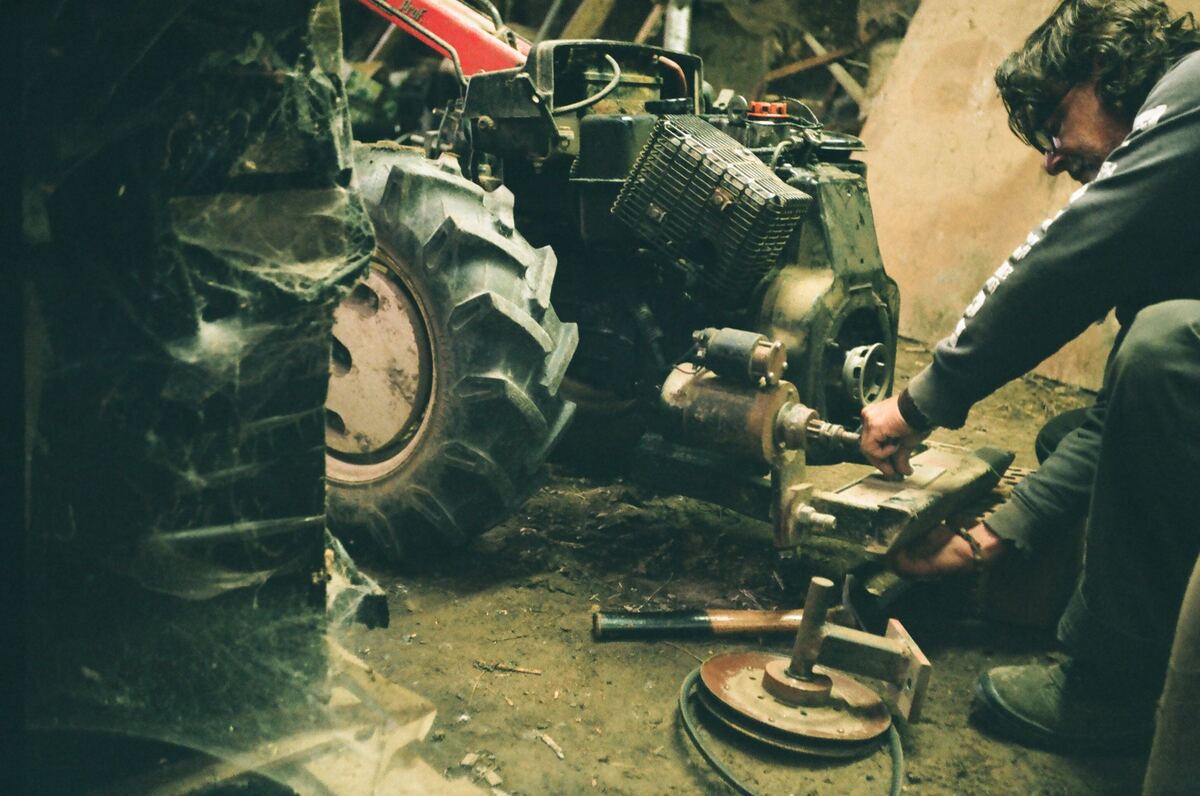 Een mecanicien werkt aan de motor van een kleine tractor
